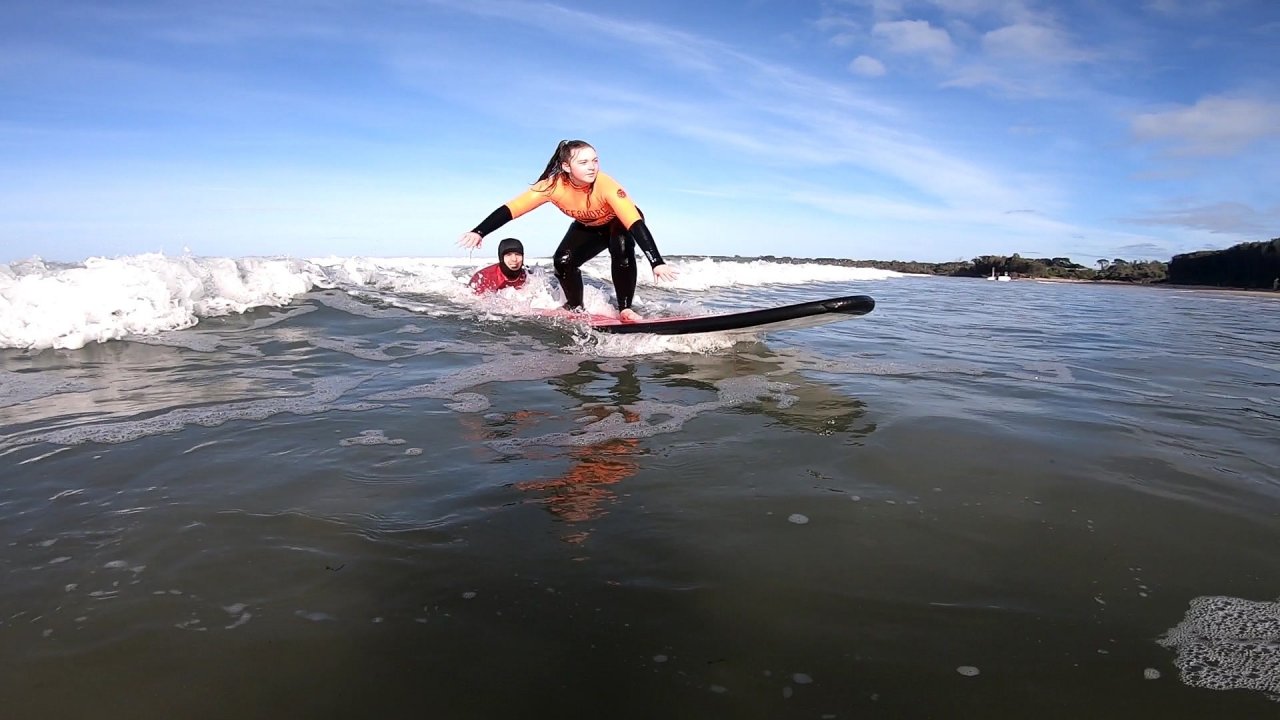 Coach Joel holding onto the back of the surfboard to help student - Offshore Surf School Inverloch 