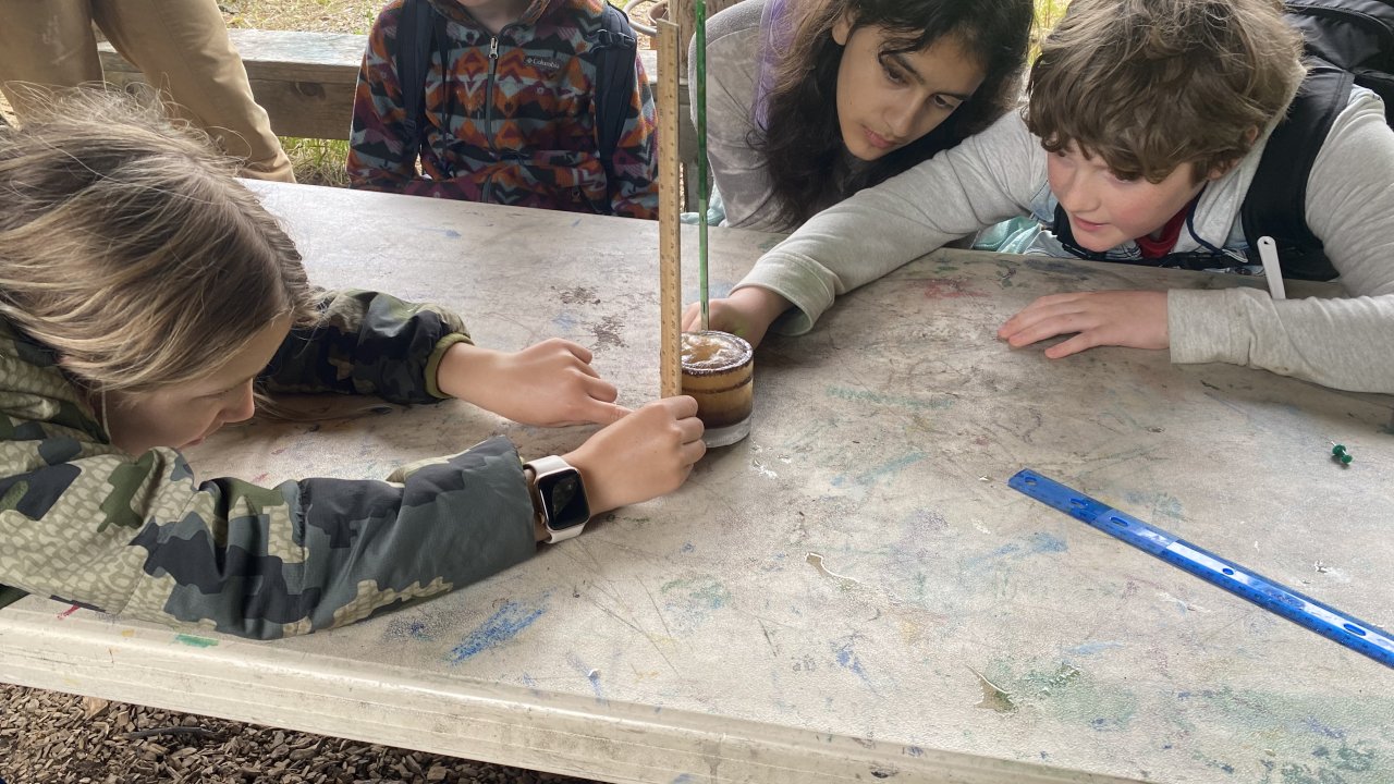 Campers measure sediment in a water sample.