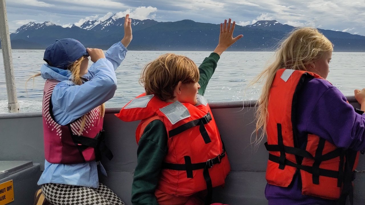 Campers on a boat wave goodbye to the Peterson Bay Field Station